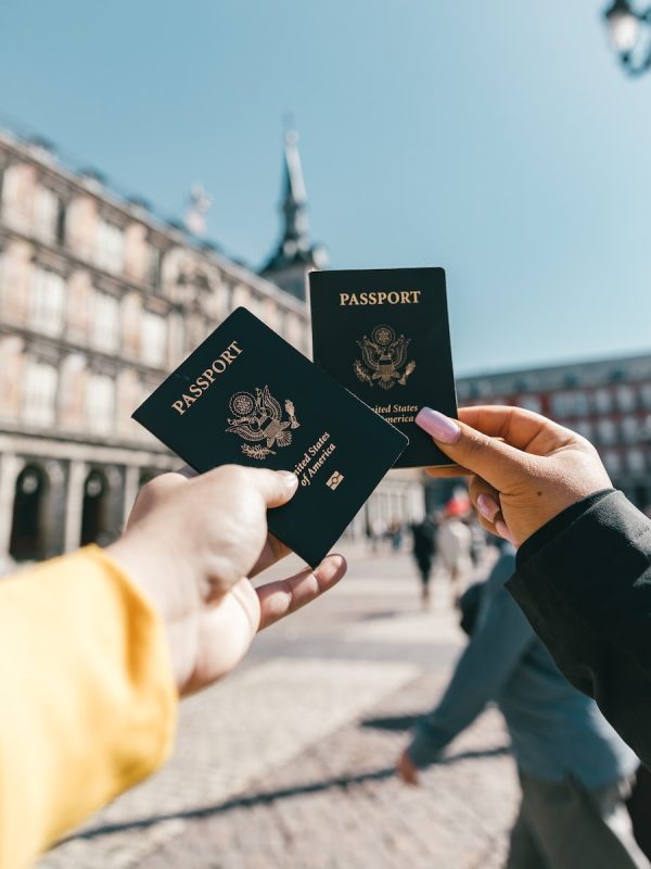 Anonymous tourists showing US passports on street on sunny day
